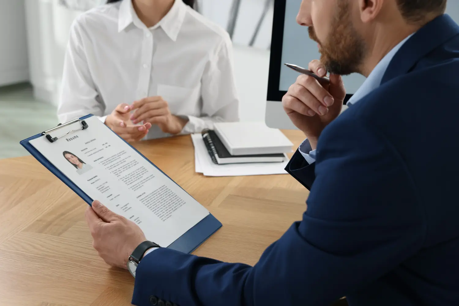 Human resources manager reading applicant's resume in office